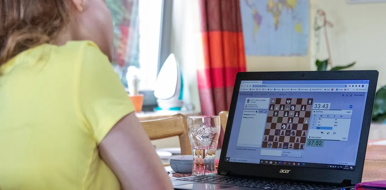 Eine Schachspielerin verfolgt ihre Onlinepartie am Laptop